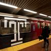 Woman standing in front of a subway car with a Temple University logo on it.